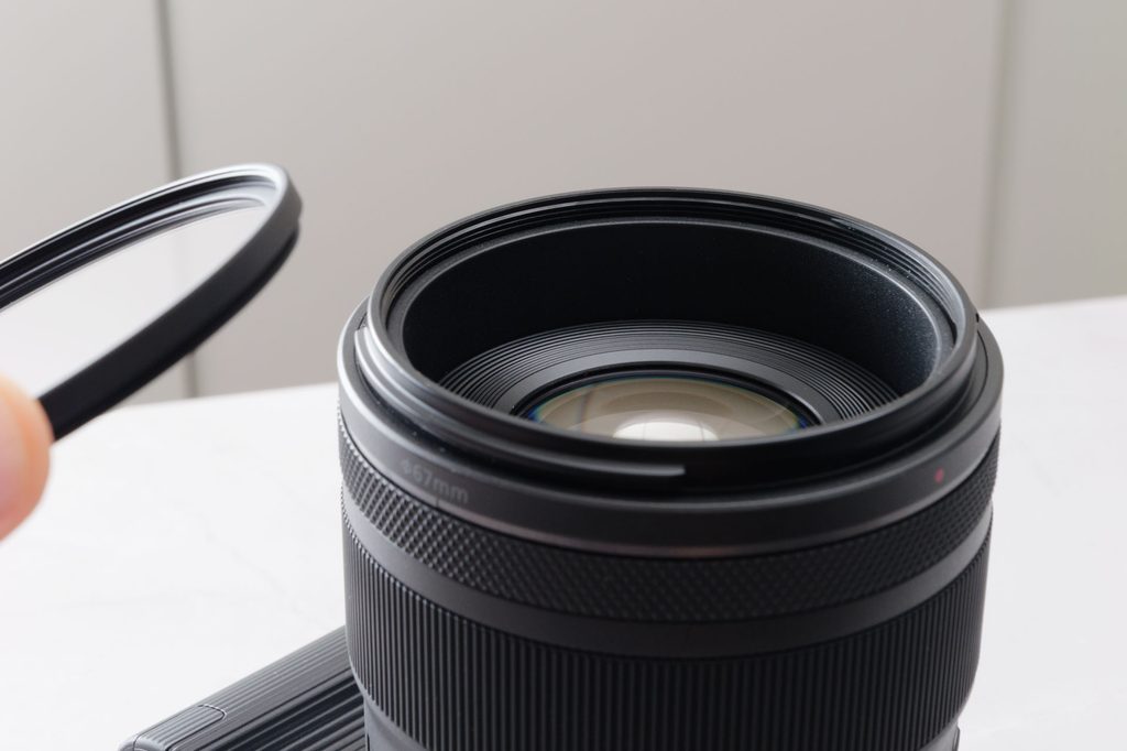 キヤノン RF45mm F1.2 STMの前玉にH&Yの保護フィルターを重ねようとしているところ