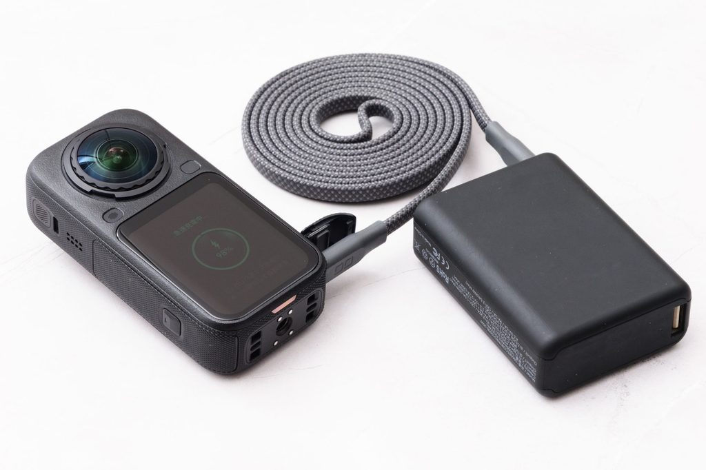 モバイルバッテリーにつないで充電中のInsta360 X6。画面に充電状況が表示されている